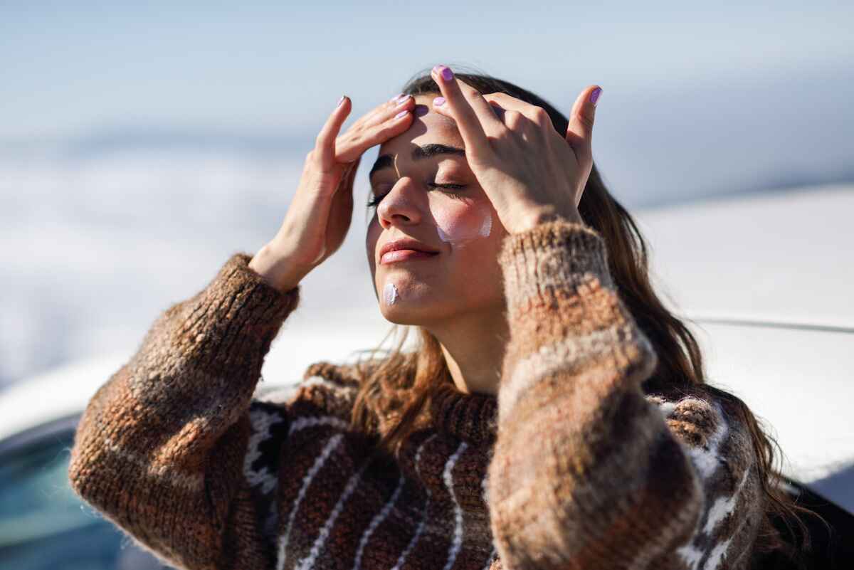 Woman follows proper winter skincare by applying sunscreen 